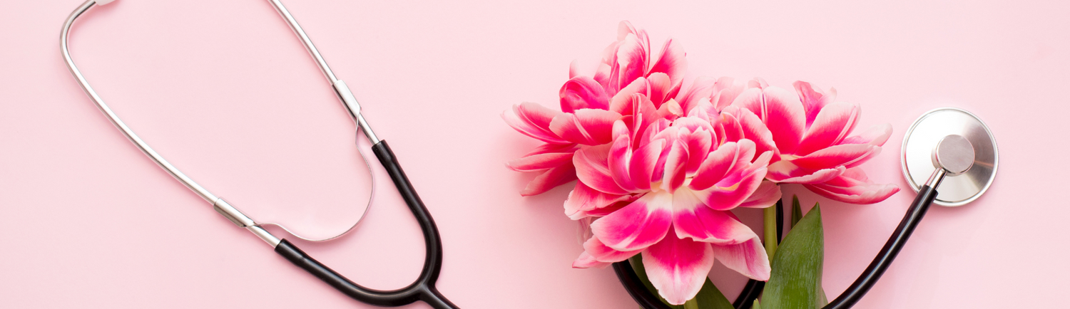 Stethoscope arranged beside pink flowers on a soft pink background, symbolizing compassion and care in nursing.