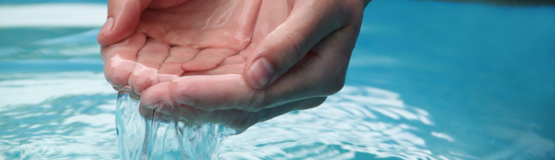 Cupped hands holding clear flowing water above a serene blue surface, symbolizing purity, hydration, and natural wellness.