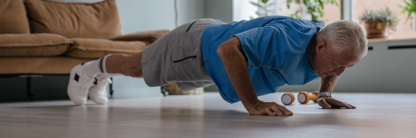 Senior man doing push-ups on the floor at home during a full-body exercise routine